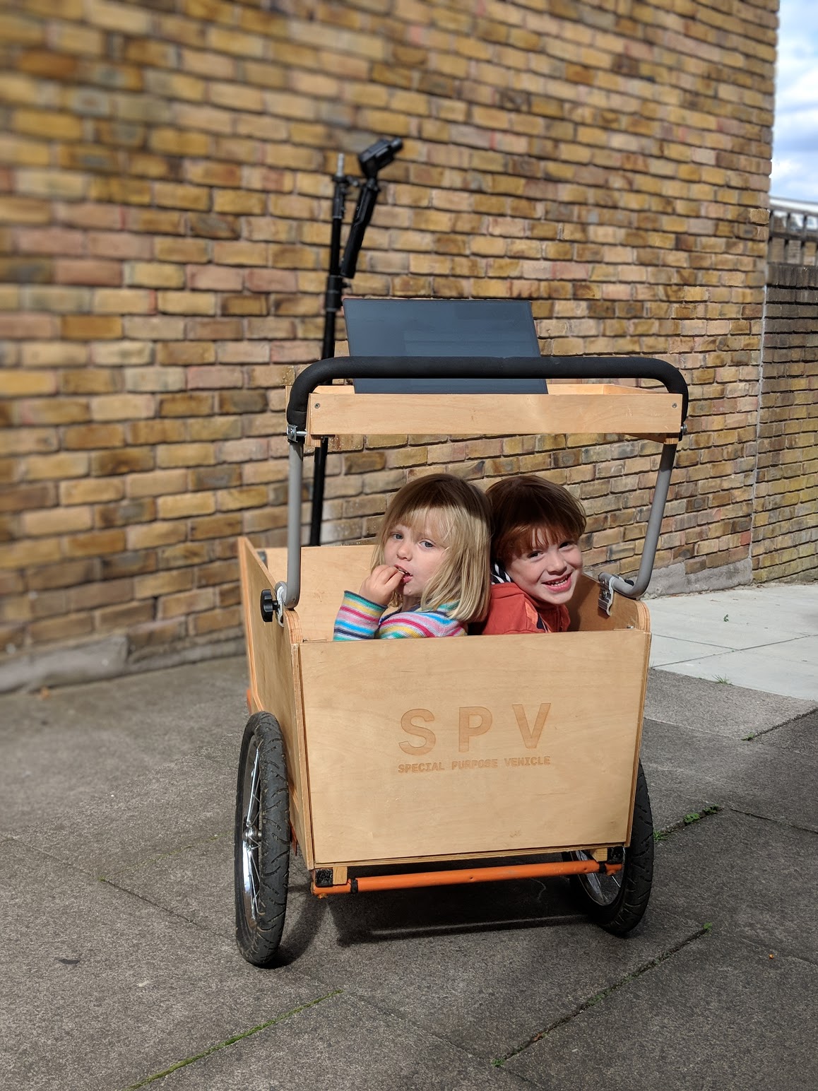 Smiling kids in a wooden bike trailer